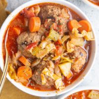 three white bowls of meatball soup with vegetables.