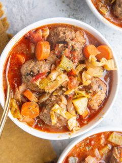 three white bowls of meatball soup with vegetables.
