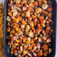 Balsamic Roasted Root Vegetables in a large casserole dish with a golden napkin to the side. Fresh out of the oven, ready to serve