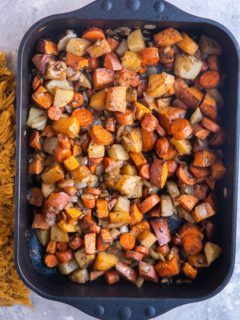 Balsamic Roasted Root Vegetables in a large casserole dish with a golden napkin to the side. Fresh out of the oven, ready to serve