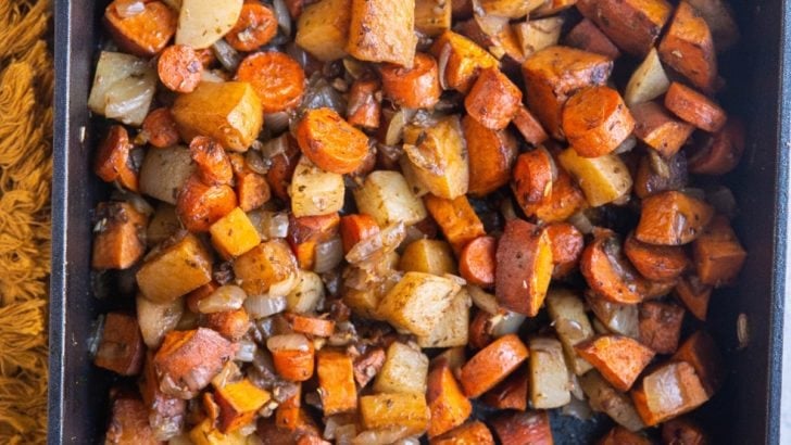 Balsamic Roasted Root Vegetables in a large casserole dish with a golden napkin to the side. Fresh out of the oven, ready to serve
