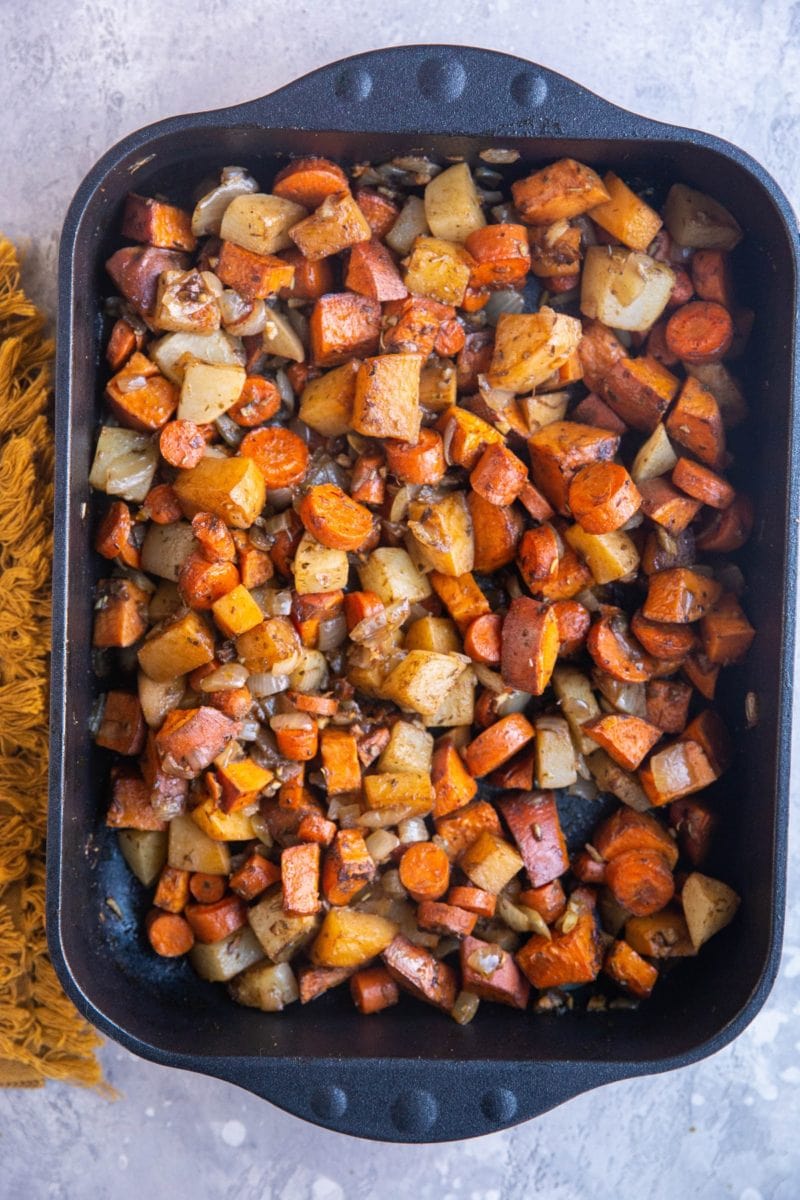 Balsamic Roasted Root Vegetables in a large casserole dish with a golden napkin to the side. Fresh out of the oven, ready to serve