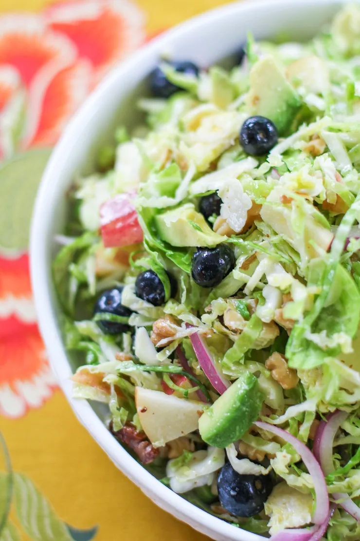 Shaved Brussels Sprouts Salad with avocado, apple, red onion, blueberries, walnuts, and citrus dressing | TheRoastedRoot.net #healthy #salad #sidedish #glutenfree #paleo #vegan