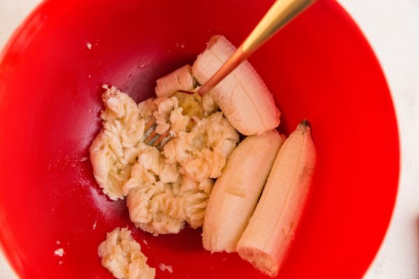 Bananas being mashed in a mixing bowl