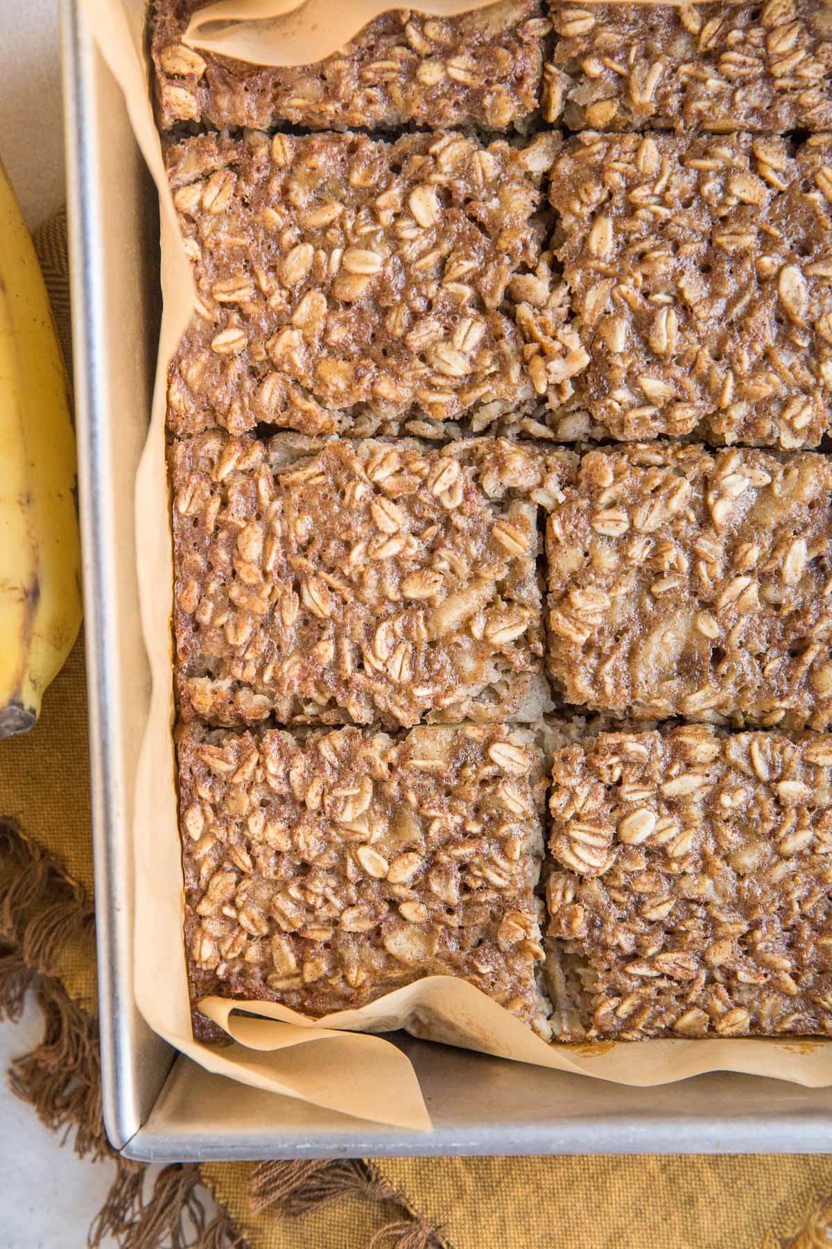 Baking pan with Banana Baked Oatmeal on top of a golden-brown napkin