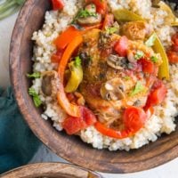 Two wooden bowls with rice and chicken cacciatore with red bell pepper, mushrooms, onion, and tomato sauce