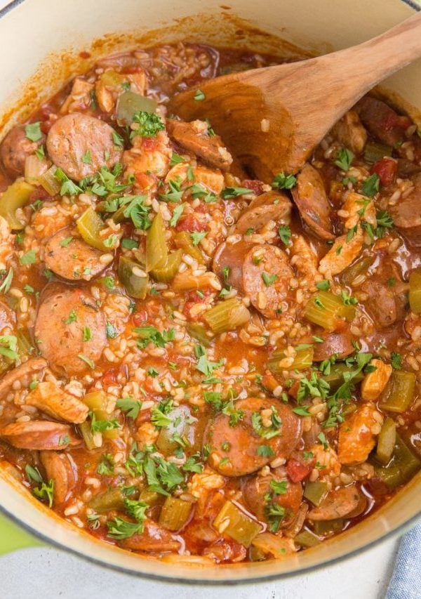 Large green pot of finished Jambalaya with a blue striped napkin to the side
