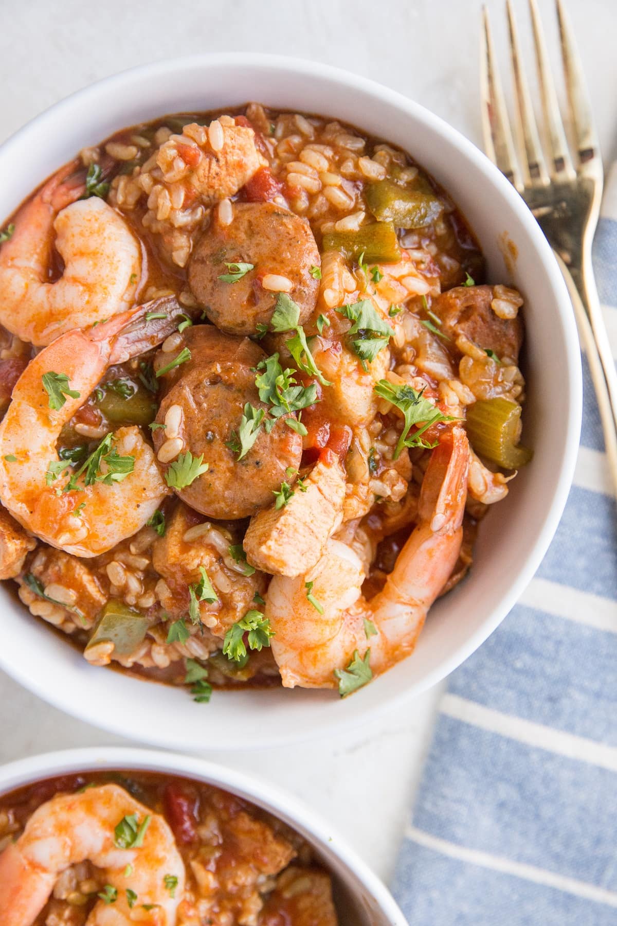 Top down photo of two bowls of jambalaya with a blue striped napkin to the side