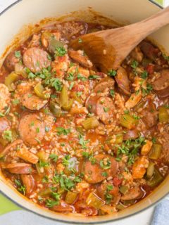 Large green pot of finished Jambalaya with a blue striped napkin to the side