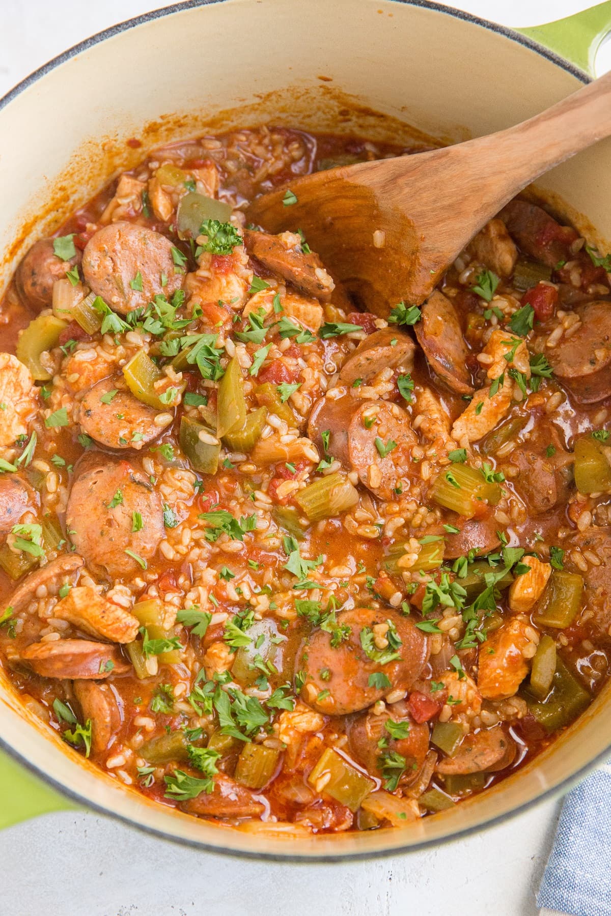 Large green pot of finished Jambalaya with a blue striped napkin to the side