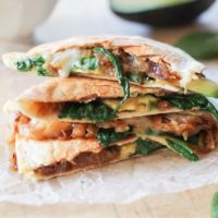 Stack of quesadillas with cheese, onion, spinach, and avocado.