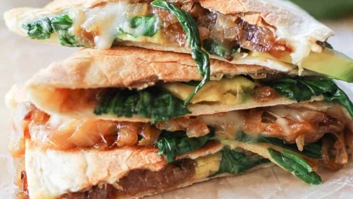 Stack of quesadillas with cheese, onion, spinach, and avocado.