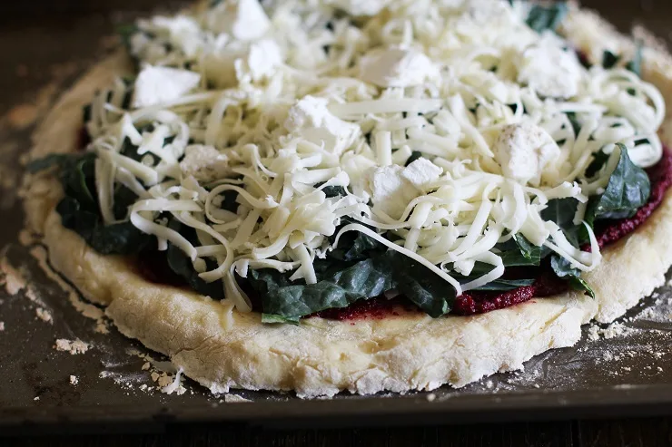 Add the kale, mozzarella cheese, and goat cheese to the beet pesto pizza