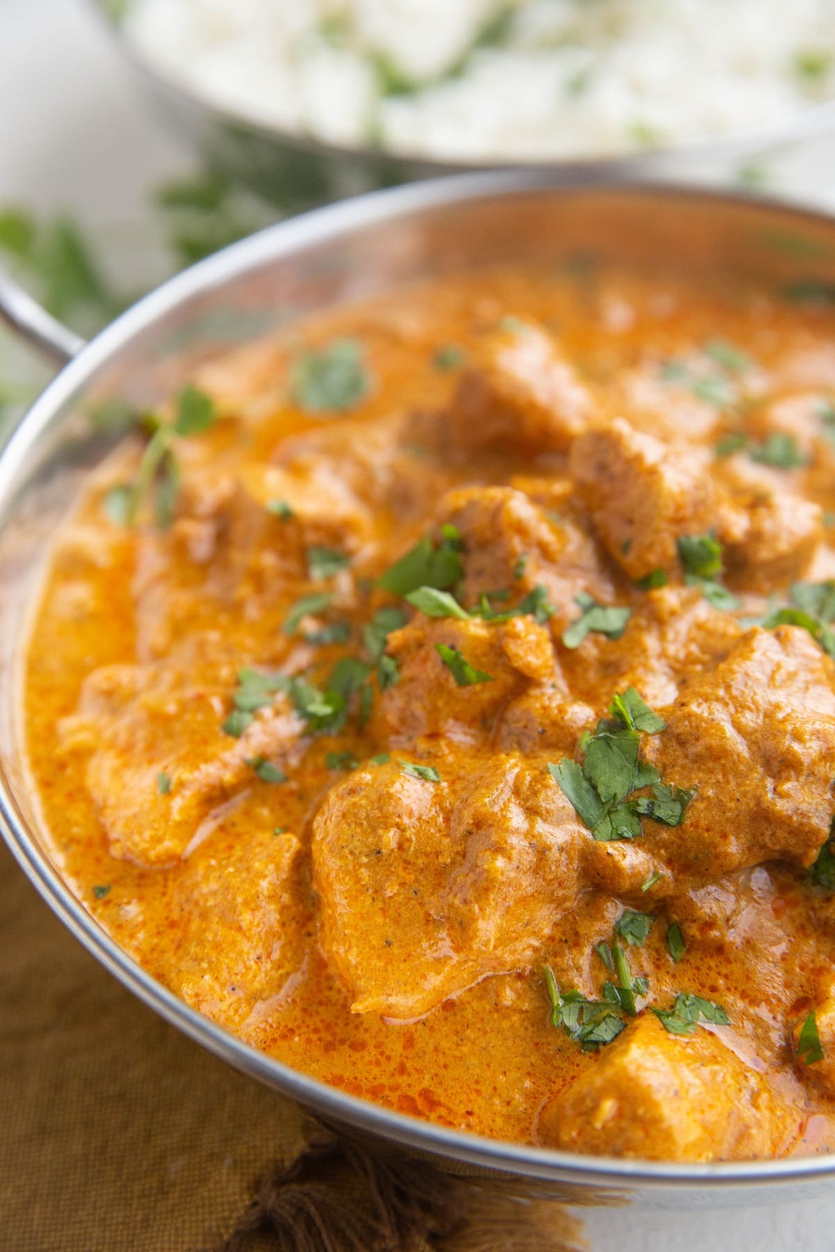 Chicken Tikka Masala in a serving dish with a serving dish of rice in the background