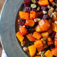 Maple Roasted Butternut Squash and Beets on a rustic wooden plate with a napkin underneath, ready to serve.