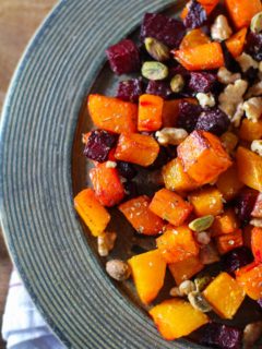 Maple Roasted Butternut Squash and Beets on a rustic wooden plate with a napkin underneath, ready to serve.