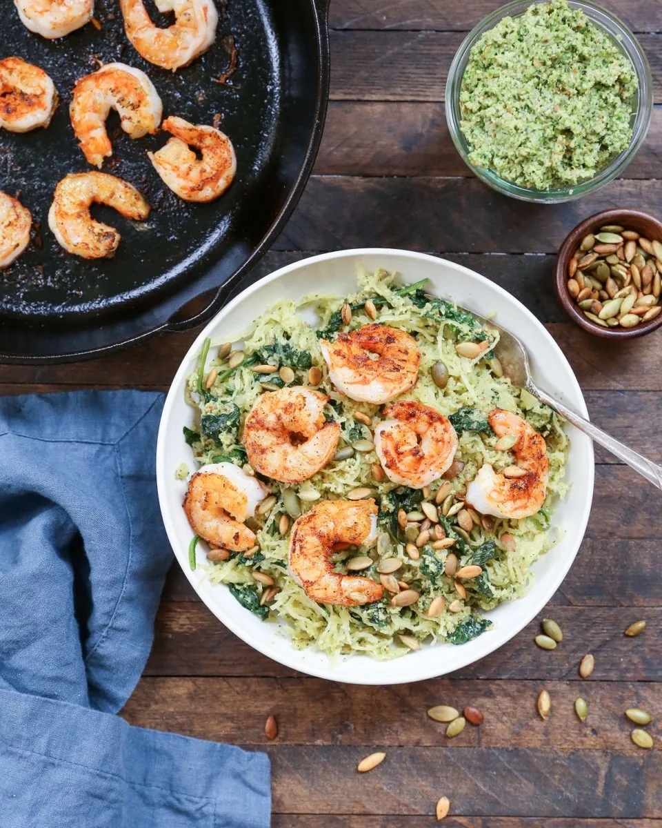 Pesto Spaghetti Squash with Basil-Parsley Pesto and Pan-Seared Shrimp in a bowl with a blue napkin to the side