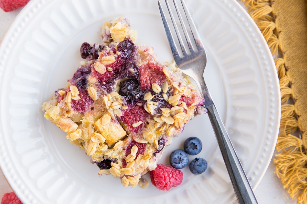 top down horizontal image of a slice of baked oatmeal on a plate with a fork and napkin