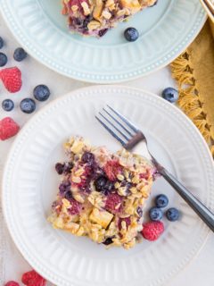 Two plates of Mixed Berry and Apple Baked Oatmeal top down with fresh berries all around
