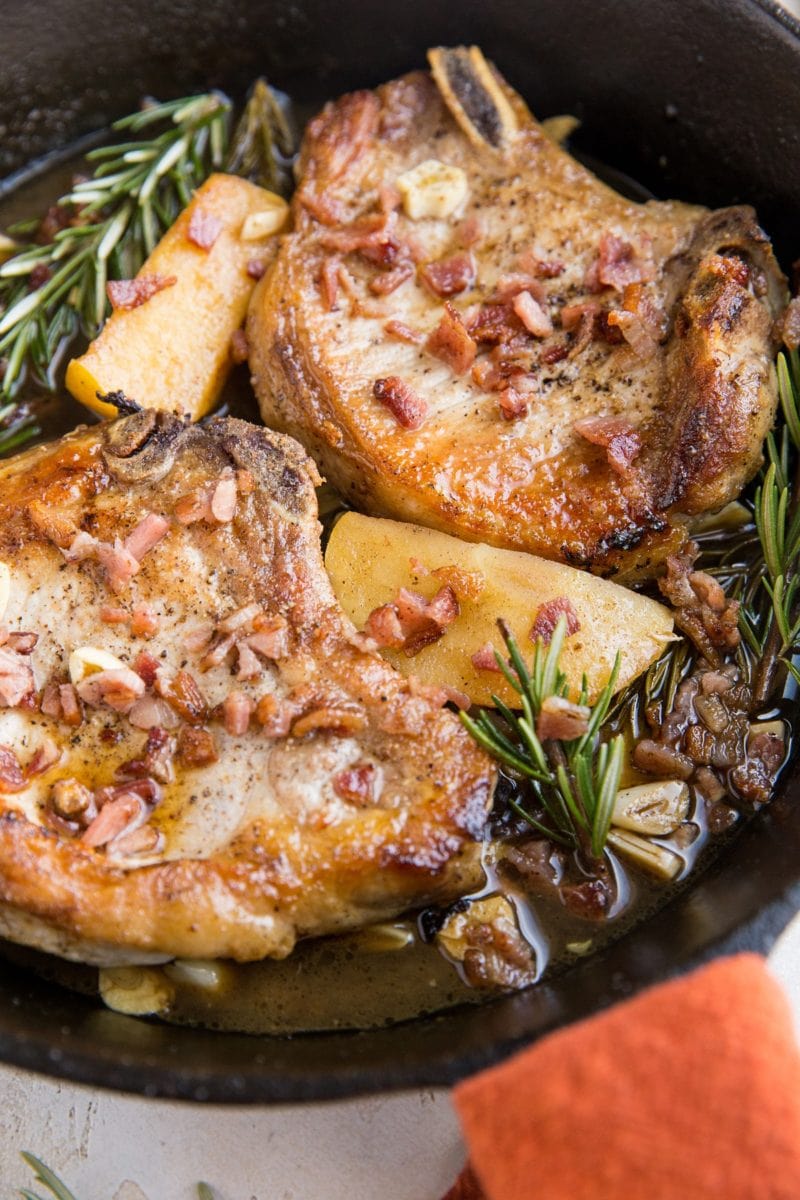 Roasted pork chops in a cast iron skillet with a red napkin around the handle