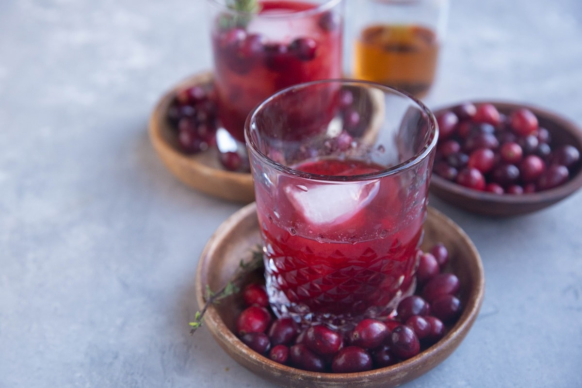 Cranberry sauce and bourbon stirred up in a glass with a large ice cube inside