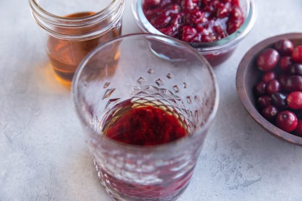 homemade cranberry sauce and bourbon in a glass ready to be made into a cocktail.