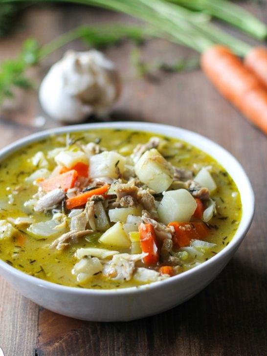 Close up white bowl of turkey soup with root vegetables