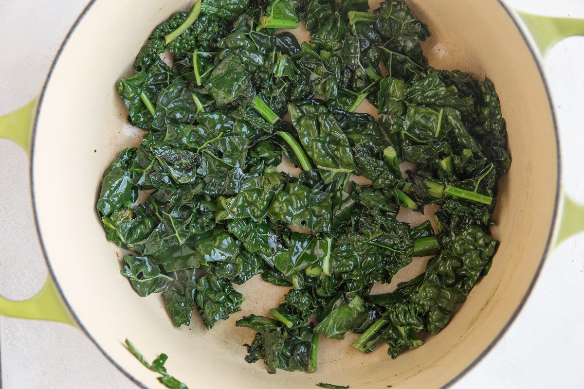 Kale being sautéed in a large pot