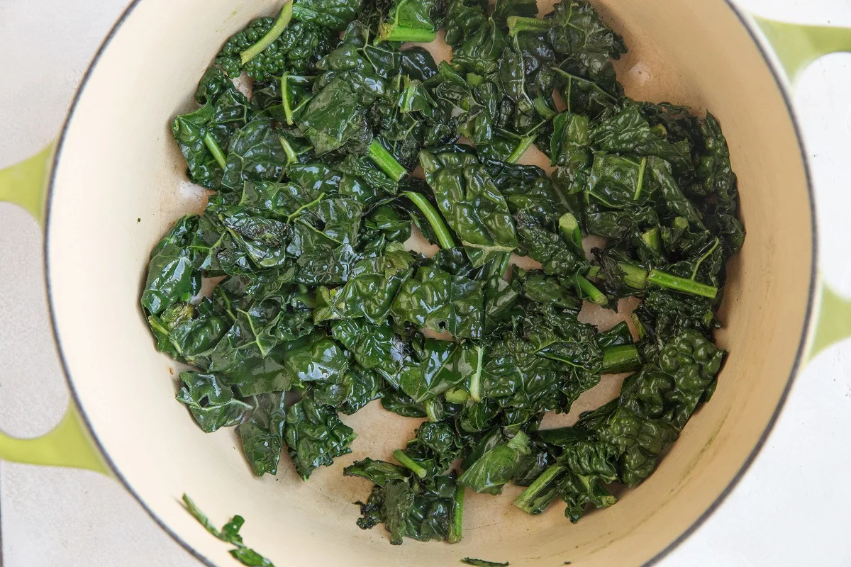 Kale being sautéed in a large pot