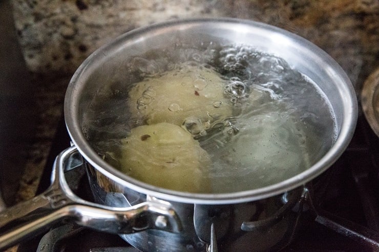 Two potatoes boiling in a pot of water for corn chowder