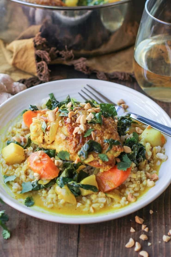 bowl of braised chicken with sauce and veggies and a fork