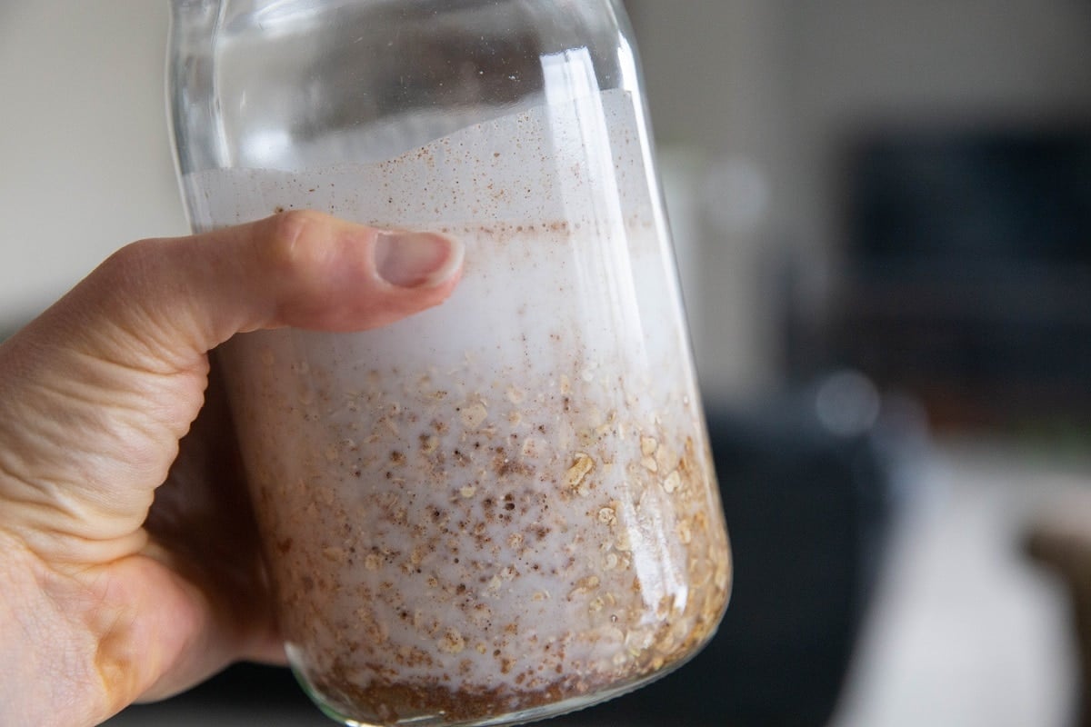 Hand holding a jar of overnight oats ingredients, shaking it up to combine everything together.