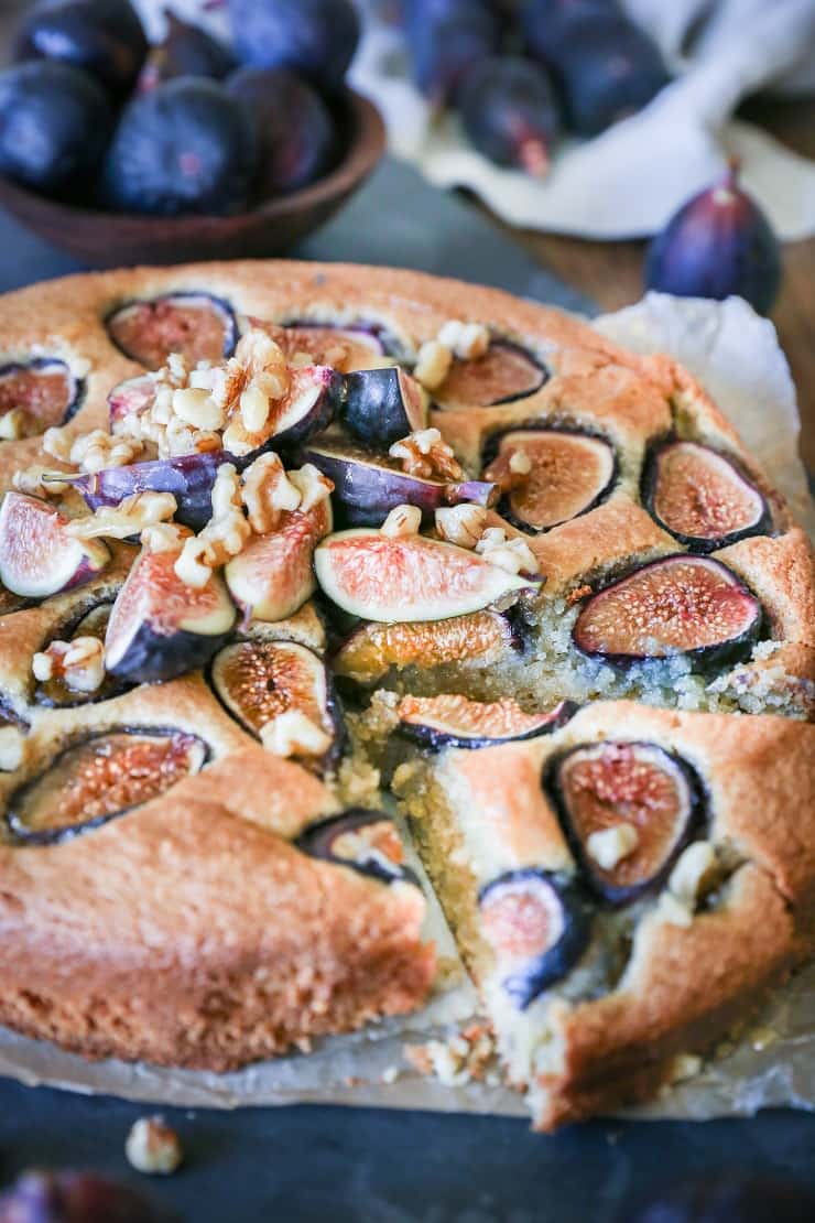 Almond flour fig cake on a cutting board with a slice cut out.