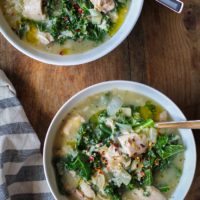 Crock Pot Chicken, Artichoke, and Kale Soup in two bowls with wood inlay spoons, ready to serve.