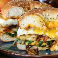 Pear Apple Cheddar Caramelized Onion Grilled Cheese Bagel Sandwiches on a plate with gooey cheese.