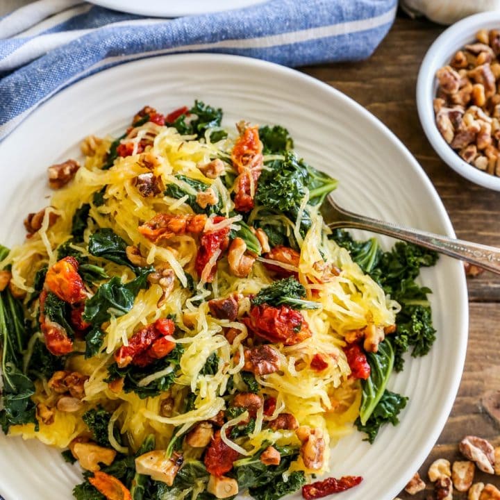 Top down photo of a white plate of Roasted Garlic and Kale Spaghetti Squash with Sun-Dried Tomatoes