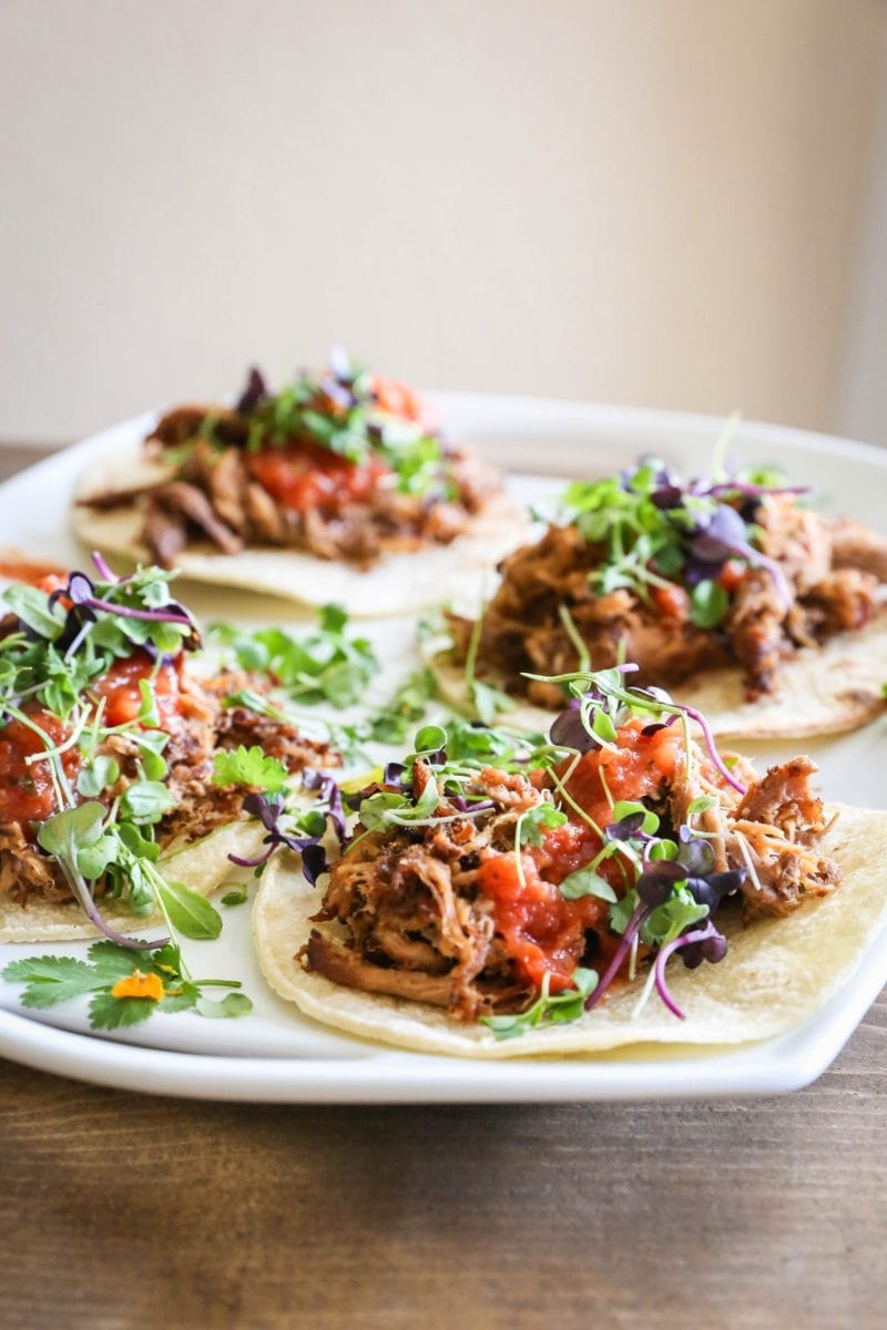 Close up platter of beef tacos with microgreens on top.