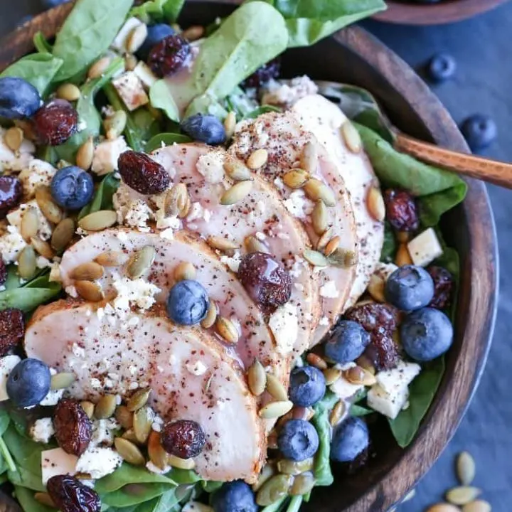 Baked Chicken Spinach Salad with dried cranberries, blueberries, feta cheese, roasted pumpkin seeds, and raspberry vinaigrette - a healthy lunch or dinner recipe