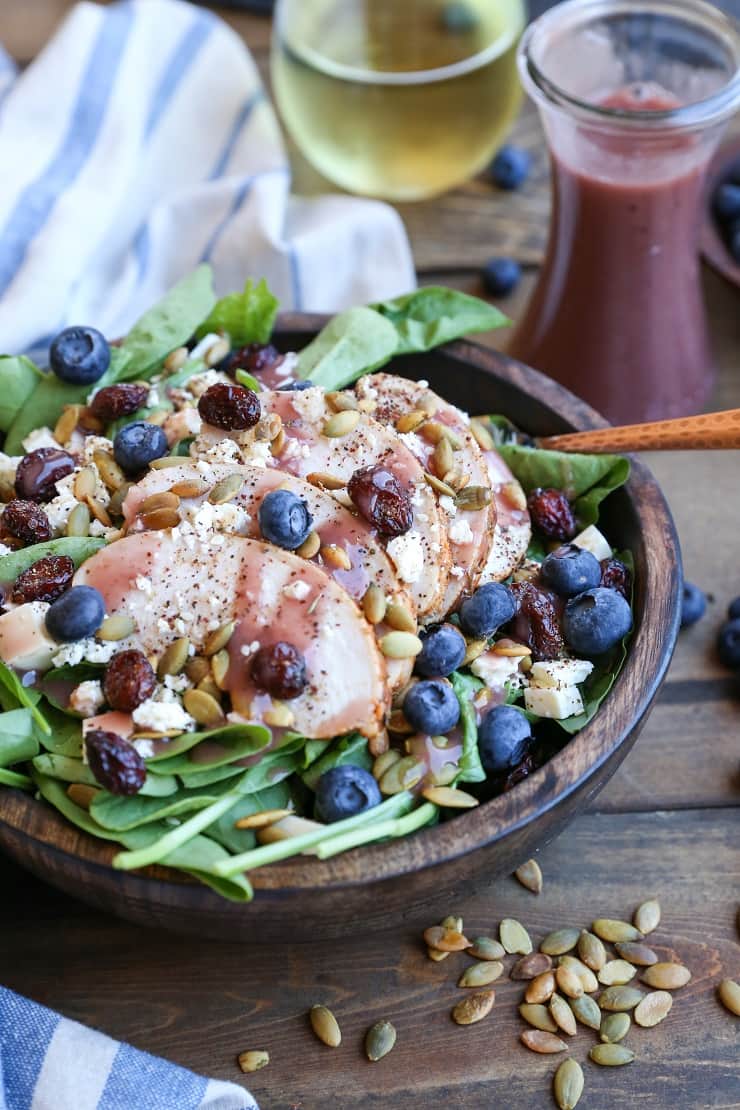 Baked Chicken Spinach Salad with dried cranberries, blueberries, feta cheese, roasted pumpkin seeds, and raspberry vinaigrette - a healthy lunch or dinner recipe