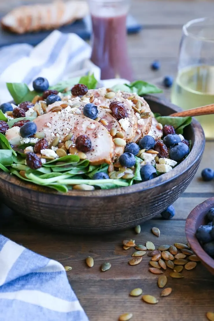 Baked Chicken Spinach Salad with dried cranberries, blueberries, feta cheese, roasted pumpkin seeds, and raspberry vinaigrette - a healthy lunch or dinner recipe