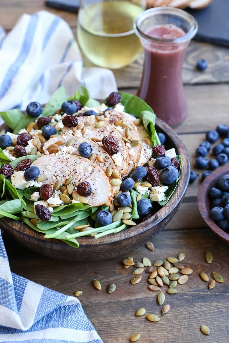 Baked Chicken Spinach Salad with dried cranberries, blueberries, feta cheese, roasted pumpkin seeds, and raspberry vinaigrette - a healthy lunch or dinner recipe