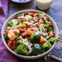 Bowl of vegetable stir fry with sauce in the background.
