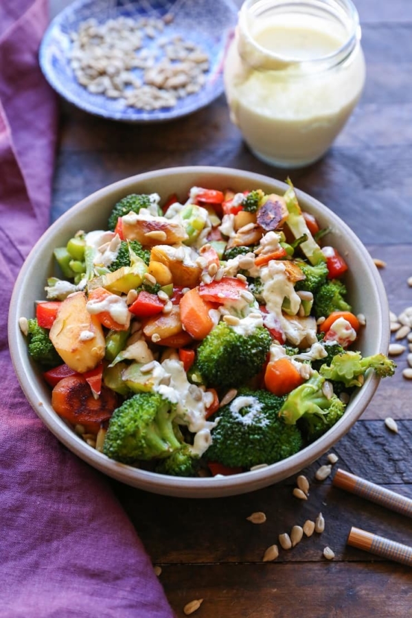 Bowl of vegetable stir fry with sauce in the background.