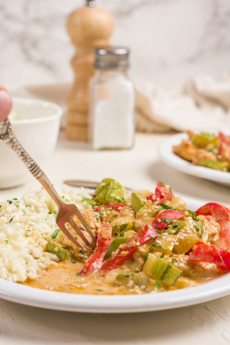 Plate of red Thai curry with a fork picking some up