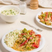 Two bowls of Thai red curry with chicken and vegetables, served with cauliflower rice.