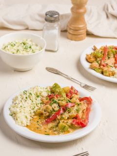 Two bowls of Thai red curry with chicken and vegetables, served with cauliflower rice.