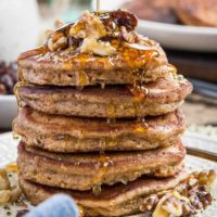 close up stack of paleo carrot cake pancakes with honey being drizzled on top