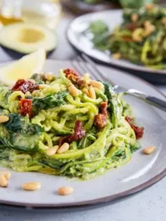 Avocado Pesto Zoodles with Sun-Dried Tomatoes, Spinach, and pine nuts. These creamy zucchini noodles are vegan, paleo, healthy, and super easy to make