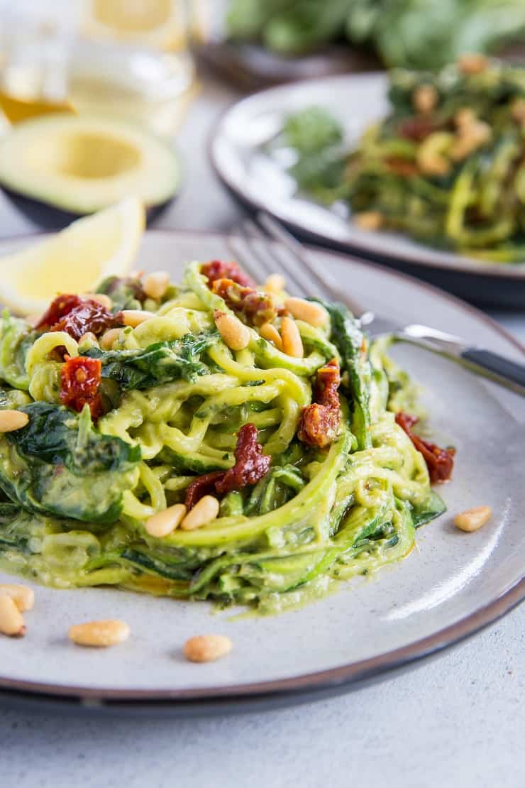 Avocado Pesto Zoodles with Sun-Dried Tomatoes, Spinach, and pine nuts. These creamy zucchini noodles are vegan, paleo, healthy, and super easy to make