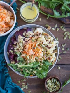 Gut Healthy Probiotic Power Bowls with roasted beets, cauliflower, dandelion greens, brown rice, sauerkraut, and orange dressing. These nutrient-rich bowls are amazing for maintaining a healthy gut.